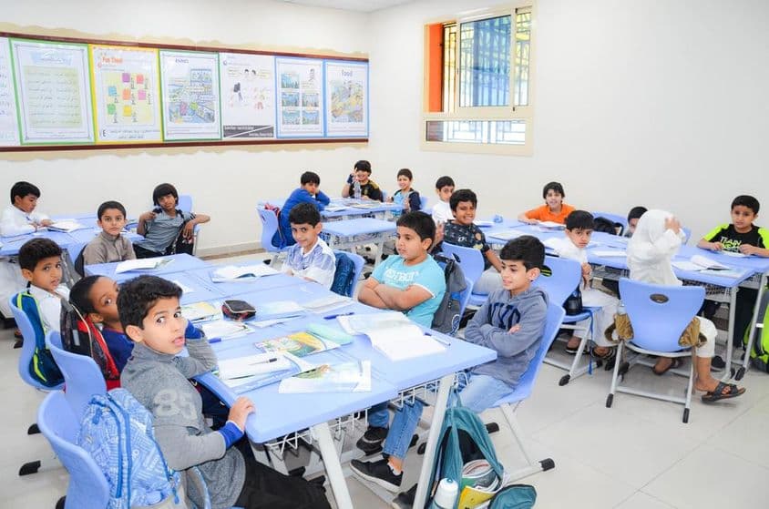 Un aula donde un grupo de estudiantes y su maestro están en una lección.