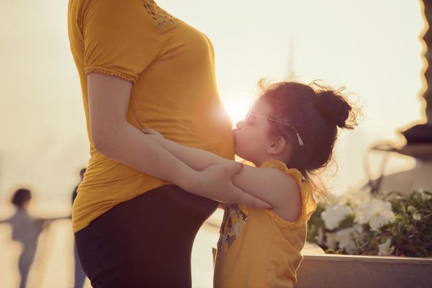 Niño besa el vientre de su madre.