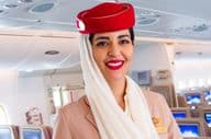 Asistente de vuelo sonriendo, aerolínea Emirates.