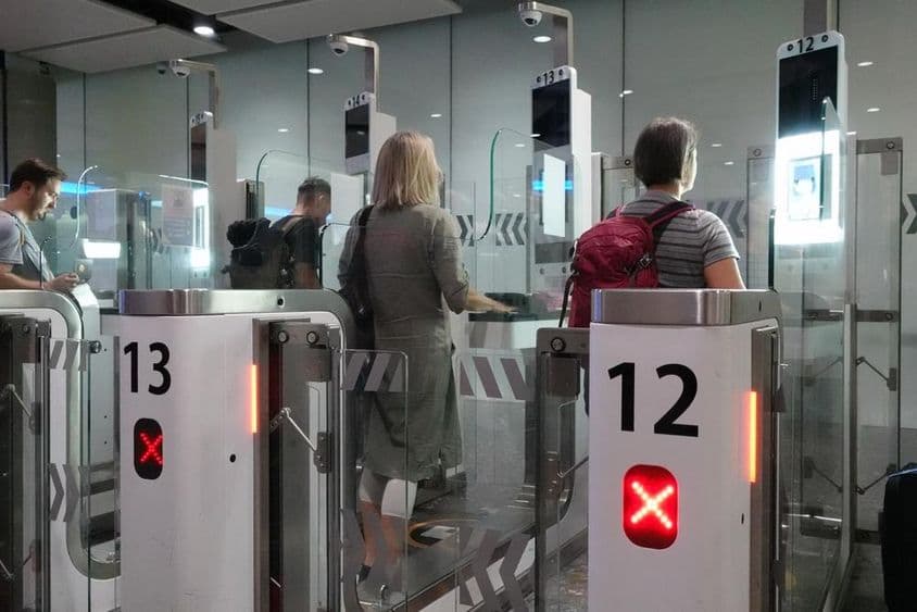 Pasajeros aéreos pasando por puntos de control de pasaporte automatizados.