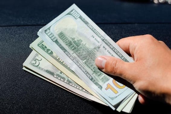 Un fajo de dólares en la mano de un hombre.