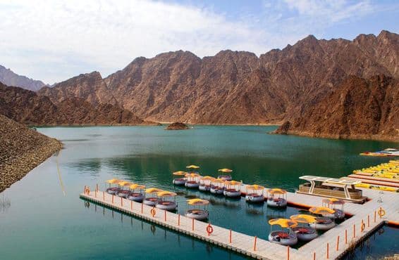 Hermoso lago verde profundo de Hatta rodeado de montañas Hajar.