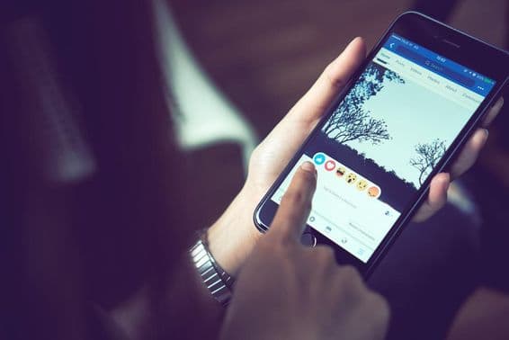 Una mano presionando Facebook en un Apple iPhone 6.