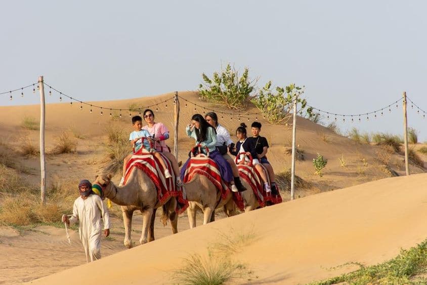 Turistas montando camellos en el desierto.