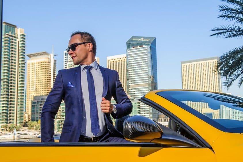 Empresario exitoso en un convertible amarillo.
