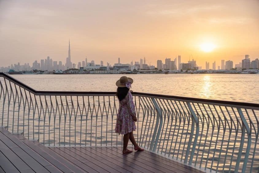 Mujer joven contemplando el horizonte de Dubái durante el atardecer.