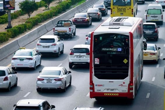 Ruta de autobús de dos pisos y tráfico diurno en las calles de la ciudad de Dubái.