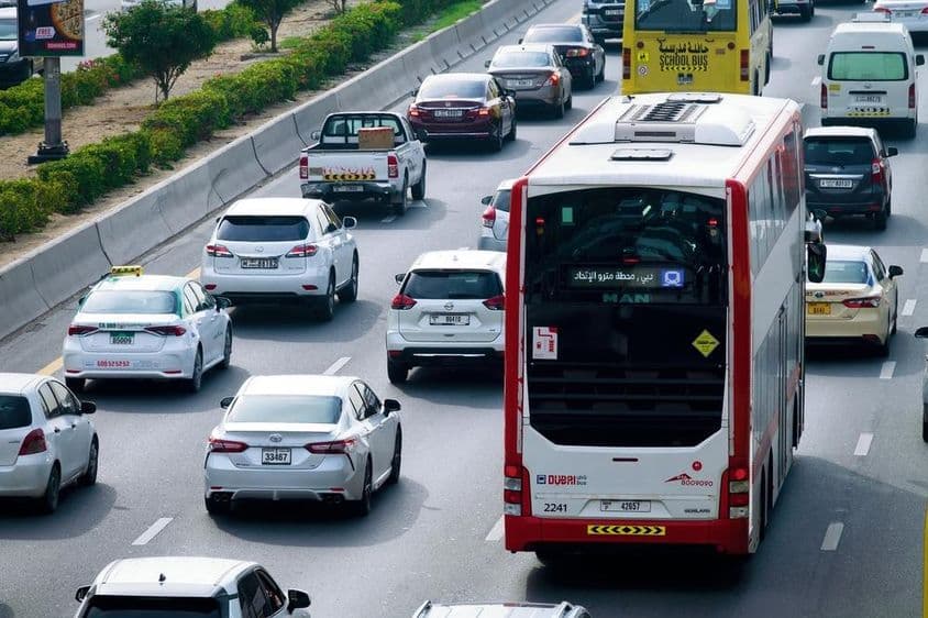 Ruta de autobús de dos pisos y tráfico diurno en las calles de la ciudad de Dubái.