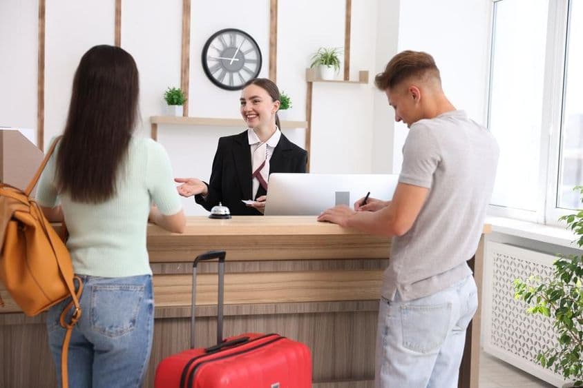 Recepcionista sonriente en uniforme con una tarjeta de llave de hotel.