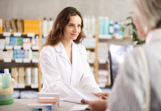 Una mujer vendiendo medicamentos en una farmacia para el manejo de enfermedades crónicas.