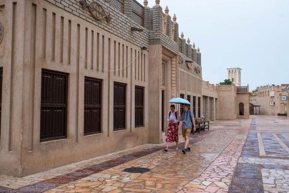 Una pareja de turistas caminando bajo un paraguas en las calles de Dubái.