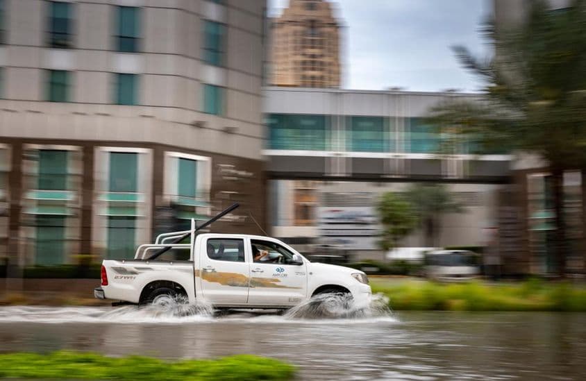 Coche conduciendo a través de una calle inundada en Dubái.