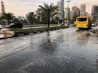 Tráfico circulando por una carretera urbana inundada en Dubái.