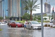 Personas empujando coches fuera del agua en calles inundadas de Dubai.