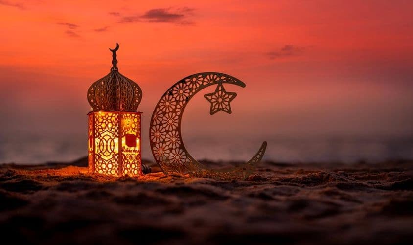 Linterna tradicional con luna creciente en la playa.