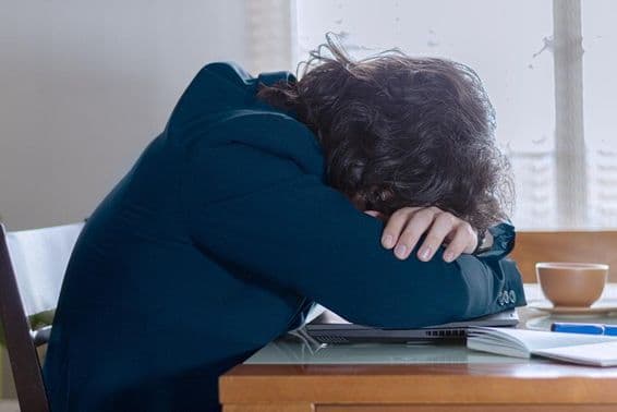 Una persona descansando sobre su computadora portátil en el trabajo un lunes.