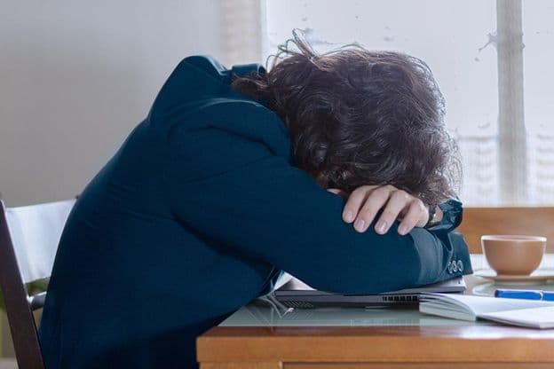 Una persona descansando sobre su computadora portátil en el trabajo un lunes.