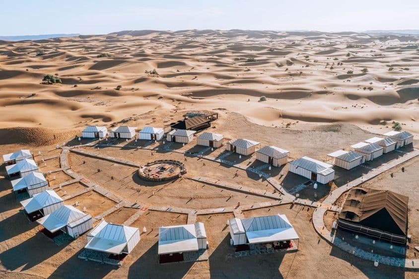 Campamento en el desierto rodeado de vastas dunas de arena.