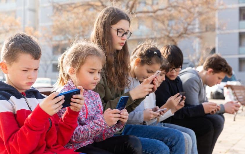 Niños comunicándose mediante mensajería en un smartphone.