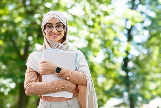 De vuelta a la escuela, mujer árabe con hijab y gafas sosteniendo libros en el parque.
