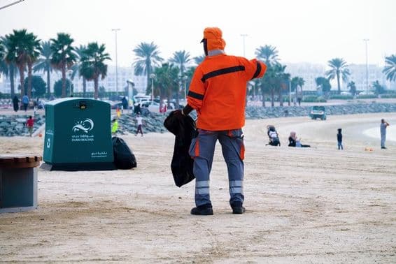 Dubái, Emiratos Árabes Unidos, trabajador limpiando la playa.