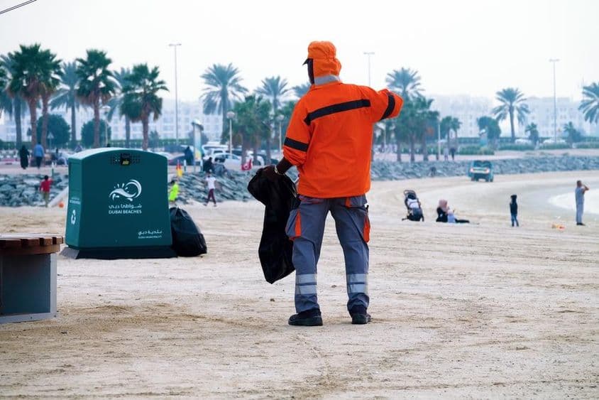 Dubái, Emiratos Árabes Unidos, trabajador limpiando la playa.