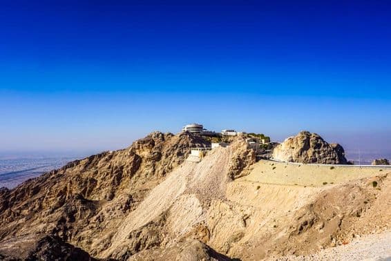 Paisaje montañoso de Jebel Hafeet en Al Ain con picos y edificios.