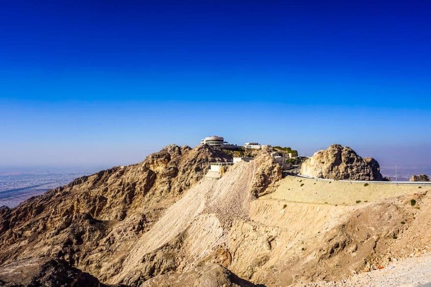 Paisaje montañoso de Jebel Hafeet en Al Ain con picos y edificios.
