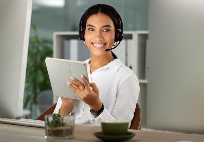 Una mujer feliz trabajando en una oficina con una tableta.