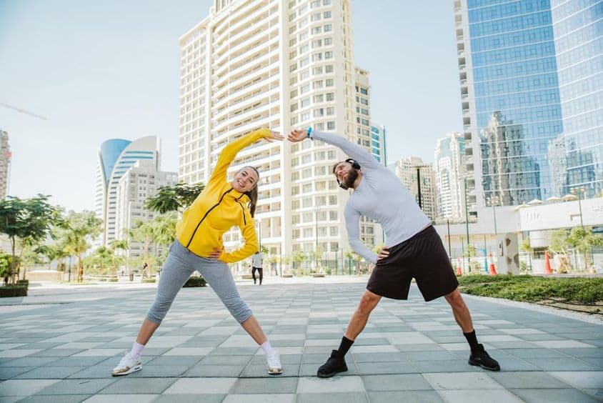 Un hombre y una mujer estirándose juntos después de un entrenamiento en Dubái.
