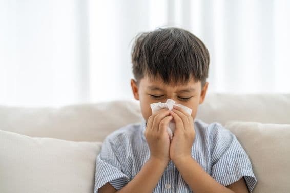 Niño asiático estornudando.