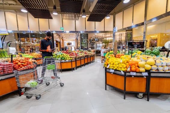 Repartidor seleccionando verduras y frutas en un supermercado.