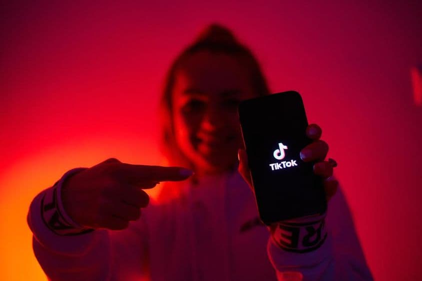 Una chica con un lado oscuro, sosteniendo un smartphone, promoviendo redes sociales.