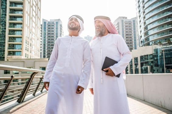 Dos empresarios en atuendo tradicional emiratí reuniéndose en Dubái.