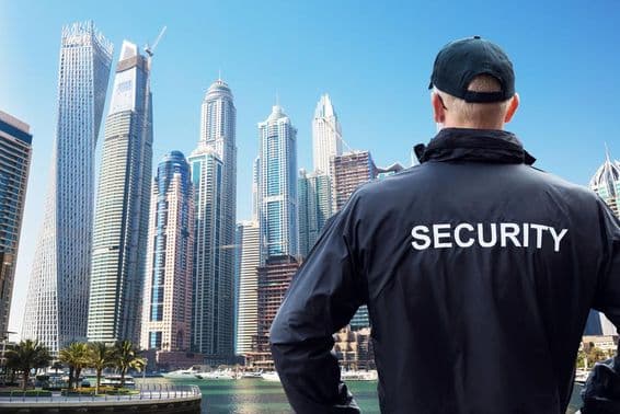 Guardia de seguridad masculino observando el horizonte de la ciudad desde atrás.