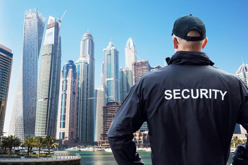 Guardia de seguridad masculino observando el horizonte de la ciudad desde atrás.
