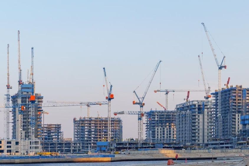 Construcción de bienes raíces en Dubai Creek Harbor, grúas, torres sin terminar.