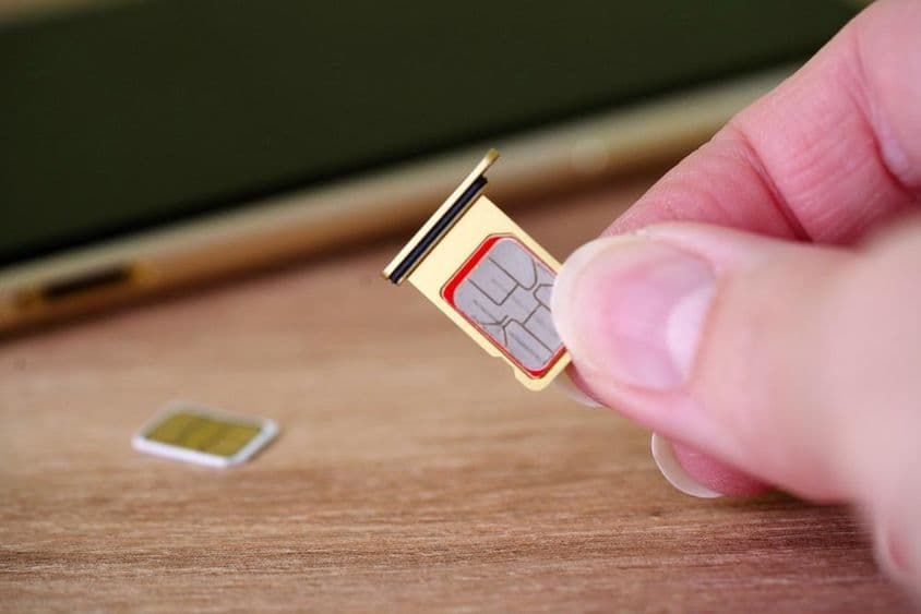 Persona insertando una tarjeta SIM en la parte trasera de un teléfono móvil.