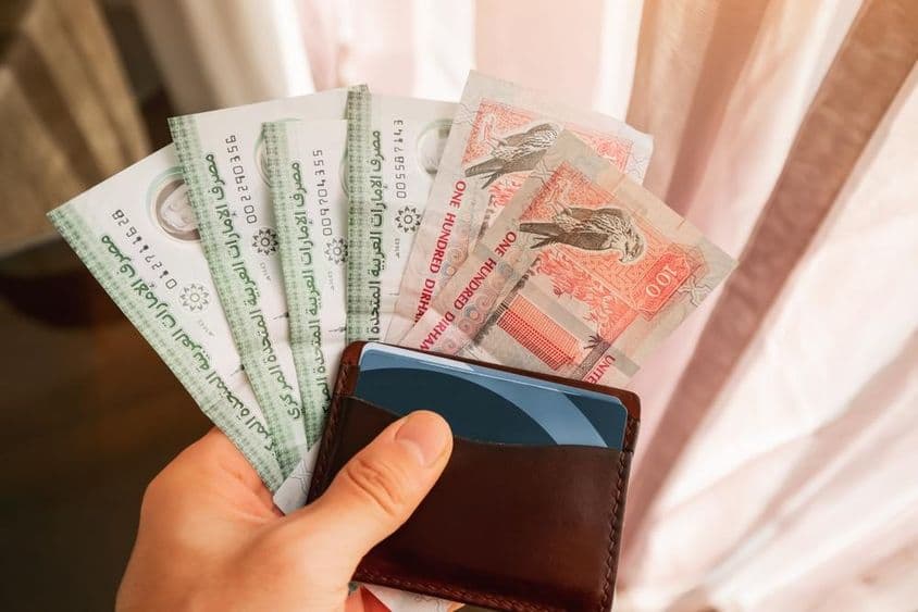 Billetes de dirham en mano y cartera.