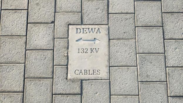 Señal de advertencia de cables en suelo de baldosas de piedra en Dubái.