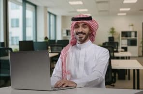 Hombre saudí sonriendo en traje tradicional trabajando.