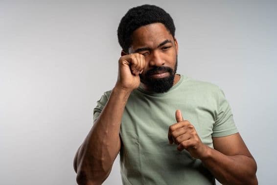 Una persona frotándose los ojos incómodamente, sintiéndose irritada y cansada.