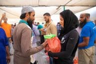 Voluntarios distribuyen paquetes de alimentos a trabajadores durante la comida de Iftar.
