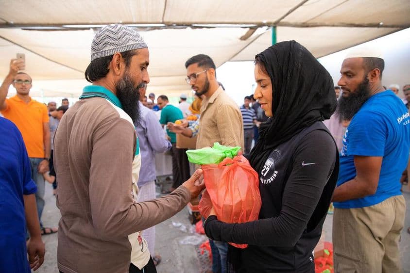 Voluntarios distribuyen paquetes de alimentos a trabajadores durante la comida de Iftar.