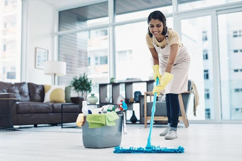 Mujer feliz limpiando con cubo y fregona.