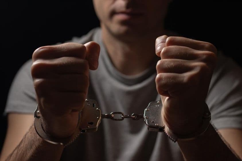 Manos sostenidas al frente con esposas.