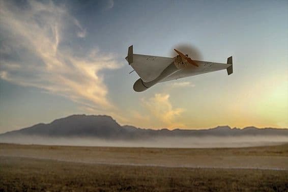 Un dron kamikaze militar volando sobre montañas desérticas.