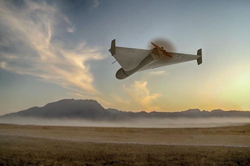 Un dron kamikaze militar volando sobre montañas desérticas.