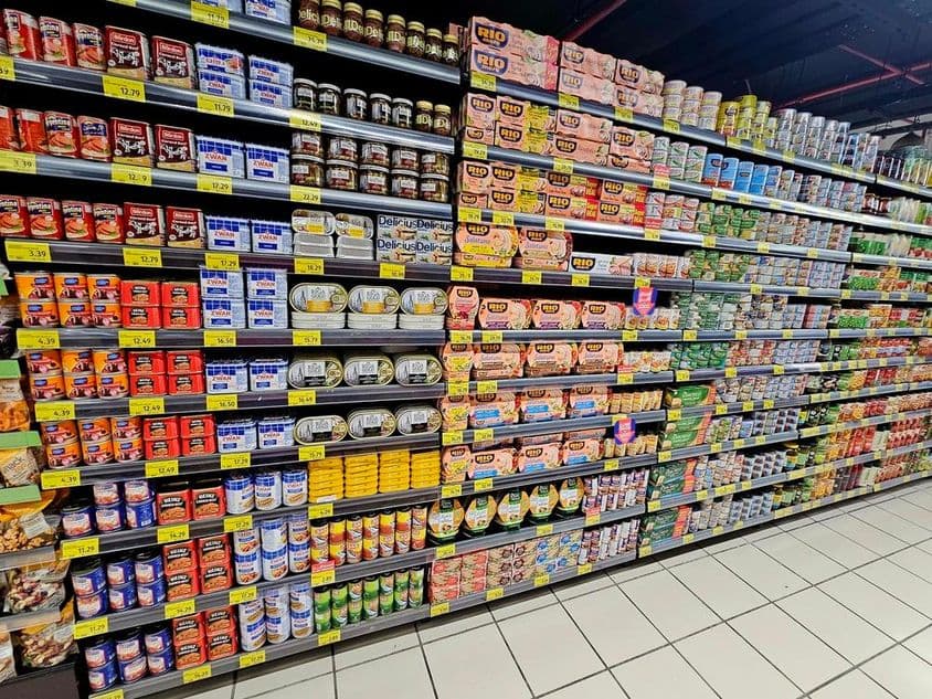 estante de supermercado con coloridas latas, atún y verduras