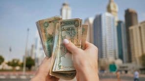 La moneda de los Emiratos Árabes Unidos contra el fondo de los rascacielos de Dubái.